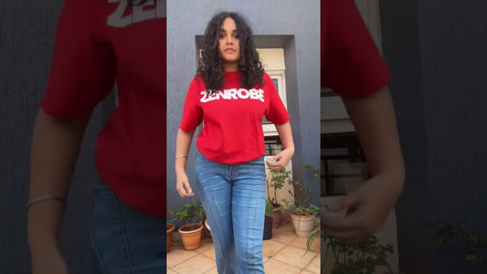 Model in a vibrant Zenrobe 240 GSM oversized t-shirt styled with blue jeans and a bold bag, showing rich color and modern fit in urban sunlight.